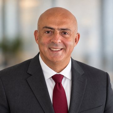 José Salloum, conseiller en sécurité financière, en complet anthracite et cravate bordeaux unie devant une fenêtre lumineuse
