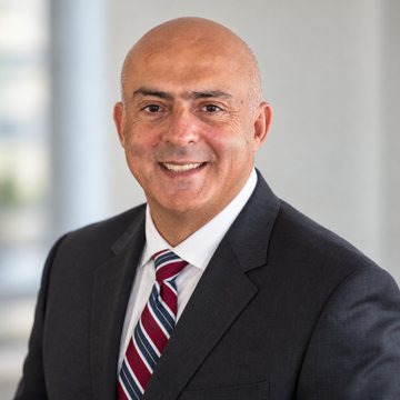 José Salloum, conseiller en sécurité financière, en complet anthracite et cravate bordeaux rayée devant une fenêtre lumineuse