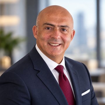 José Salloum, conseiller en sécurité financière au Canada, en complet foncé avec pochette, la ville derrière lui