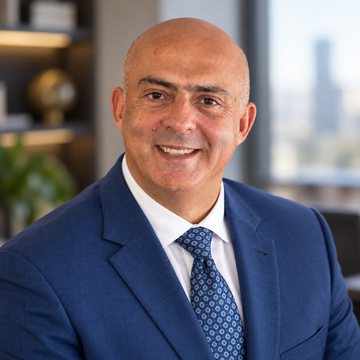 José Salloum, conseiller en sécurité financière, en complet marine et cravate à motifs, la ville au crépuscule derrière lui