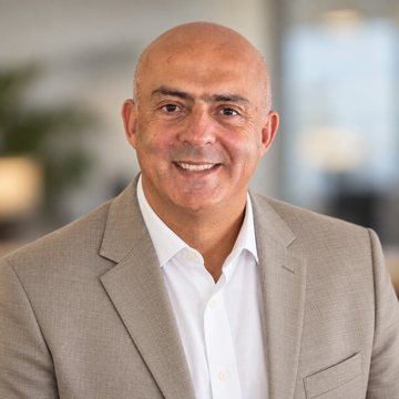 Jose Salloum, Infinite Banking practitioner, in a tan jacket and an open white shirt in a bright daylit room