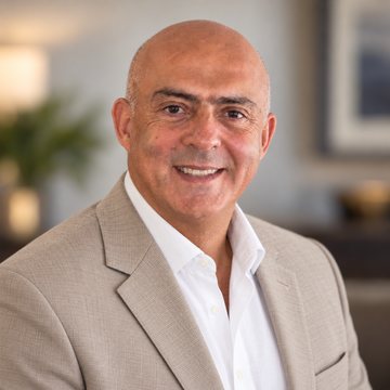 Jose Salloum, Infinite Banking practitioner, in a tan jacket and an open white shirt in a warm sitting room