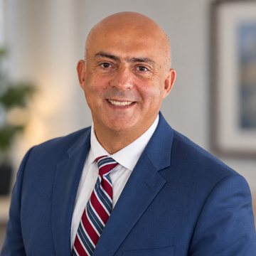 Jose Salloum, Infinite Banking practitioner, in a navy suit and a burgundy striped tie in a Montreal office